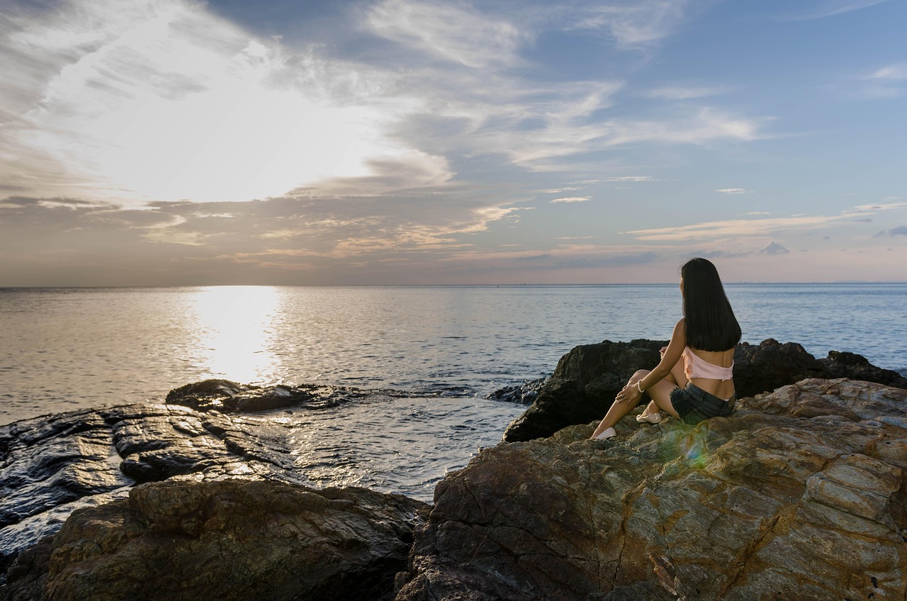 woman, beach, sit, sitting, sunset, dusk, sunrise, dawn, young woman, rocks, rock formations, rocky beach, rocky shore, nature, coast, shore, seascape, ocean, horizon, alone, solitary, solitude, waiting, girl, young