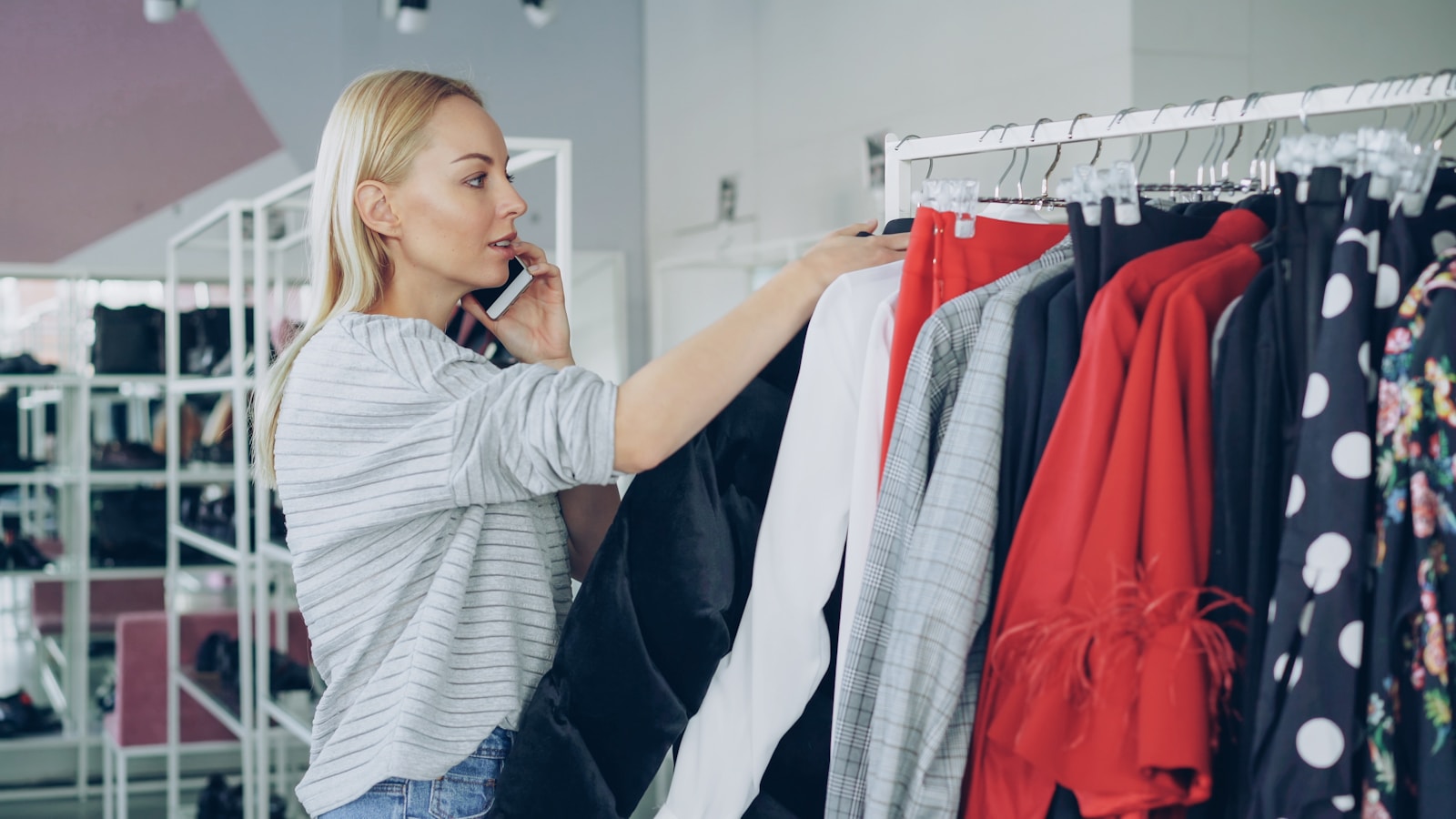 Woman shops for clothes while on the phone.